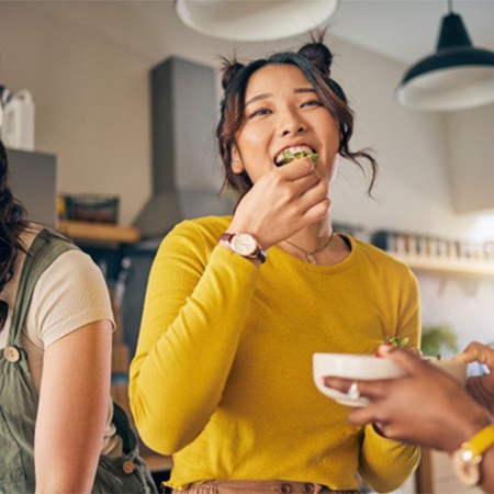 Group of friends smiling while enjoying snack in kitchen