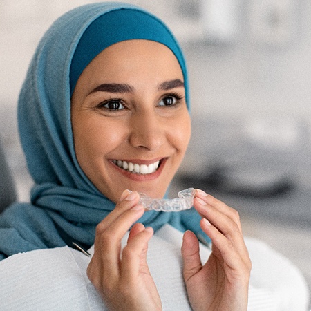 Young woman putting on Invisalign tray 