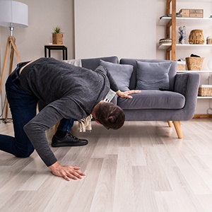 Man looking for something under couch