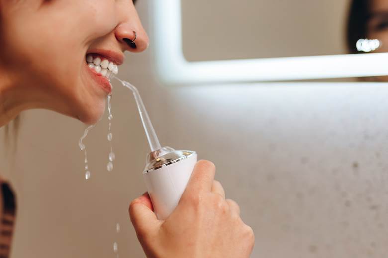 Woman using water flosser to clean between her teeth